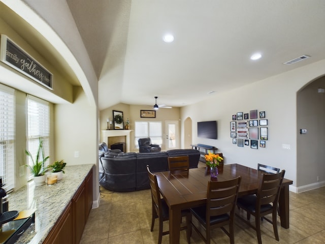 dining area with a wealth of natural light, arched walkways, visible vents, and a fireplace