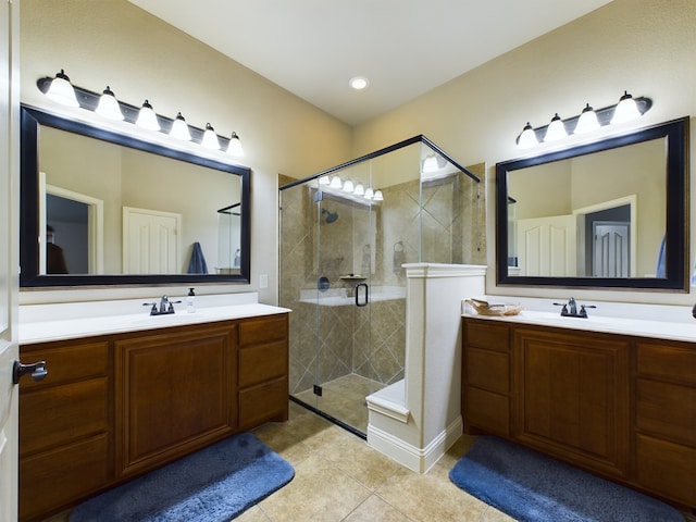 full bath with a stall shower, two vanities, and a sink