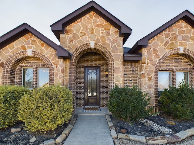 property entrance with stone siding and brick siding