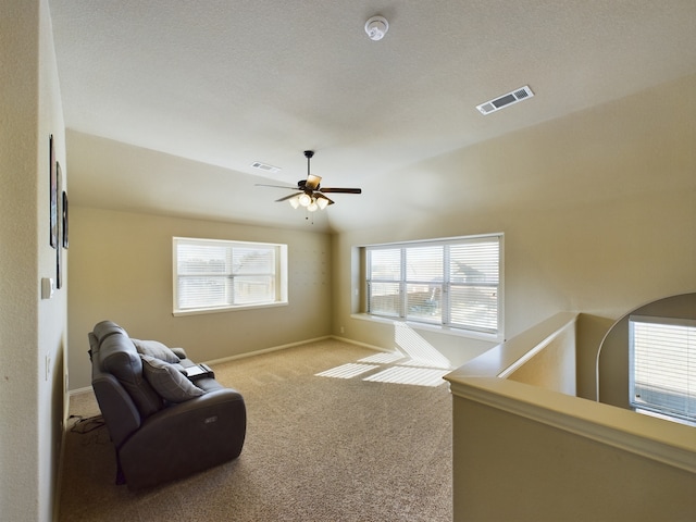 living area with baseboards, visible vents, ceiling fan, and light colored carpet