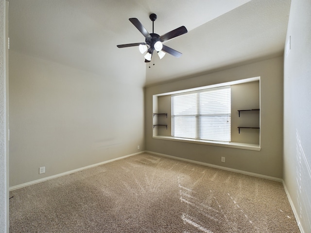 carpeted spare room featuring ceiling fan, baseboards, and vaulted ceiling