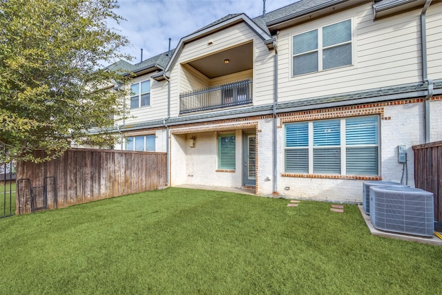 back of house featuring a yard, brick siding, cooling unit, and fence