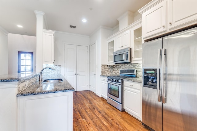 kitchen featuring white cabinets, glass insert cabinets, appliances with stainless steel finishes, dark wood-style flooring, and a sink