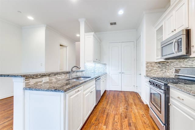 kitchen featuring a peninsula, white cabinetry, appliances with stainless steel finishes, and a sink