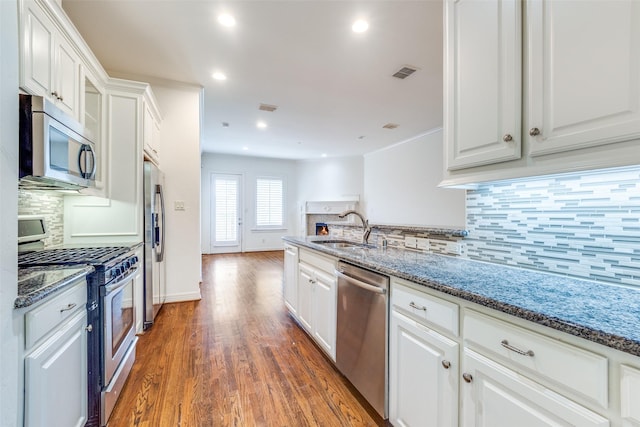 kitchen with stainless steel appliances, stone counters, white cabinetry, and a sink