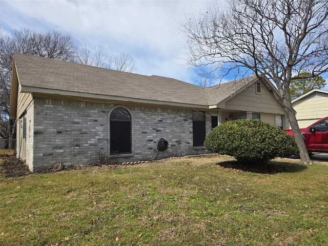 ranch-style house with a front yard, brick siding, and roof with shingles