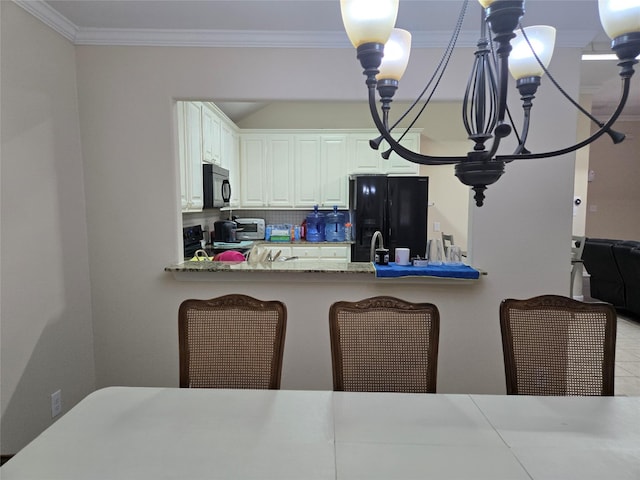 kitchen featuring white cabinetry, ornamental molding, black appliances, tasteful backsplash, and decorative light fixtures