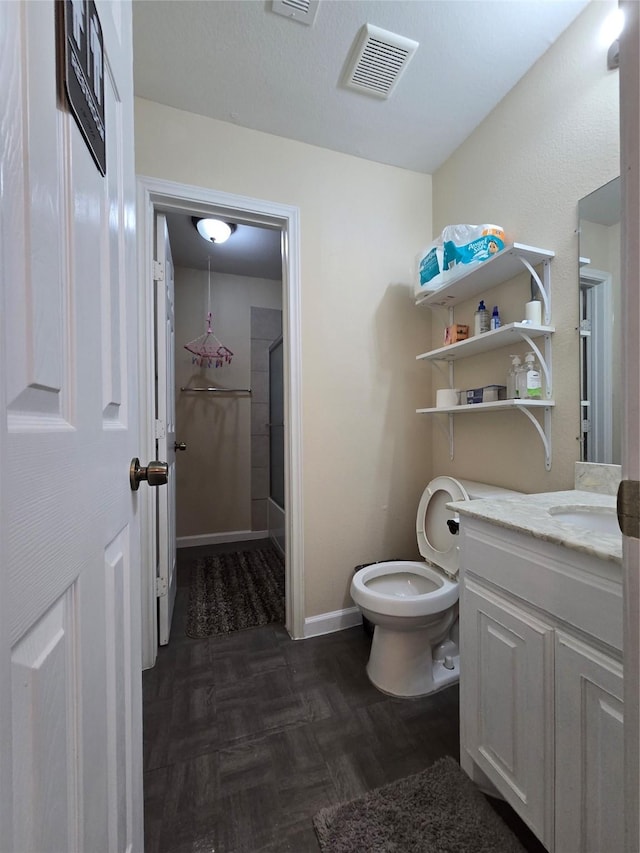 bathroom featuring toilet, vanity, visible vents, baseboards, and an enclosed shower