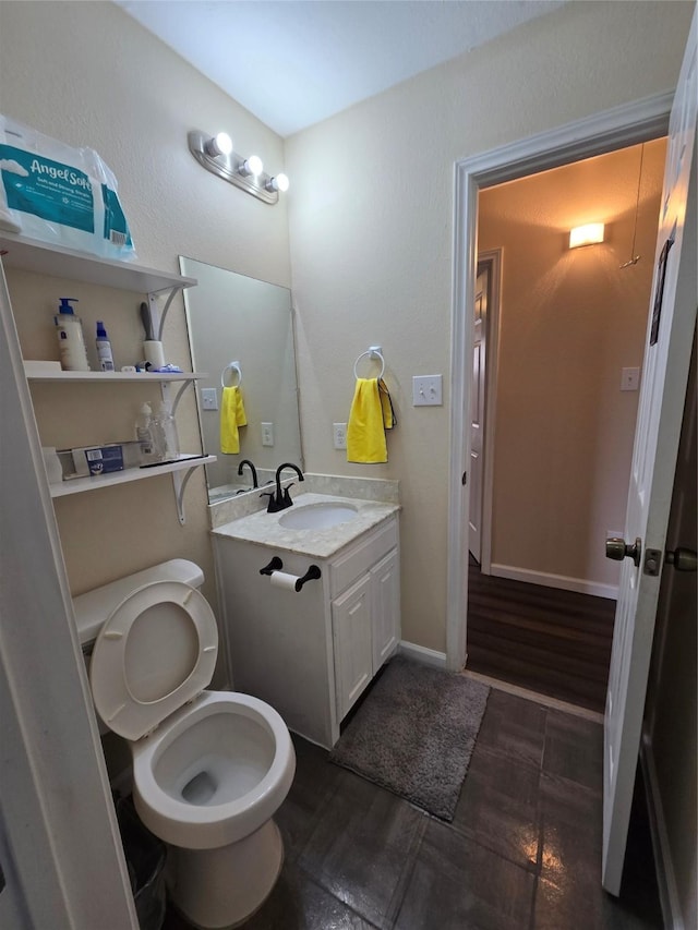 half bath featuring baseboards, vanity, toilet, and wood finished floors