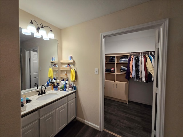 bathroom with a walk in closet, vanity, baseboards, and wood finished floors