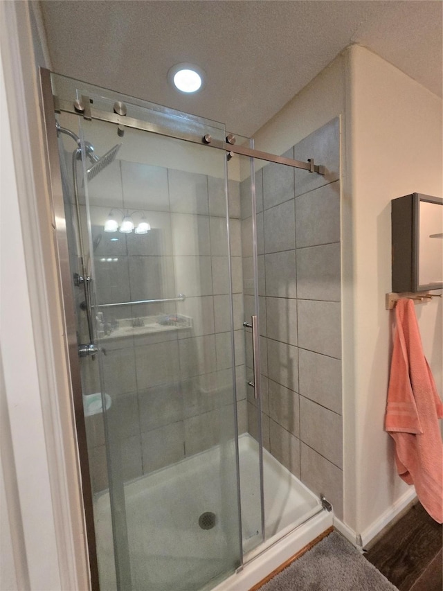 bathroom with wood finished floors, a shower stall, and baseboards