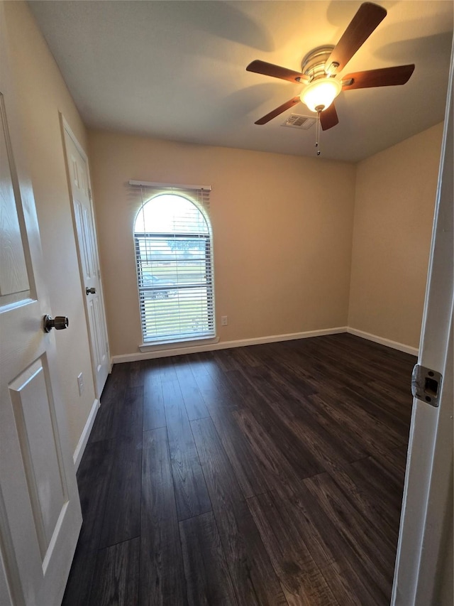 spare room featuring a ceiling fan, visible vents, baseboards, and dark wood-style flooring