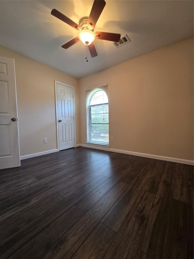 unfurnished room featuring a ceiling fan, dark wood-style flooring, visible vents, and baseboards