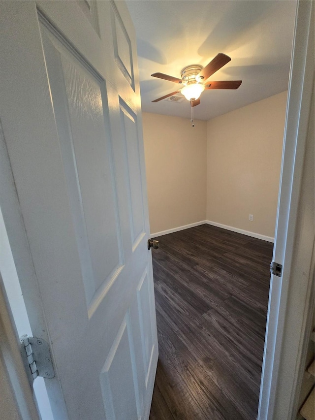 empty room with dark wood-style floors, baseboards, and a ceiling fan