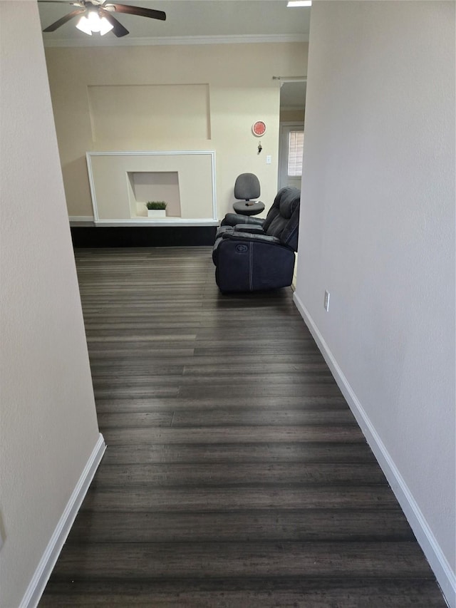 corridor with dark wood finished floors, crown molding, and baseboards