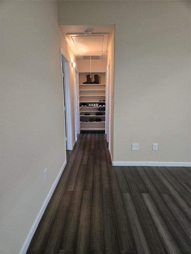 hall with dark wood-style floors, visible vents, built in shelves, and baseboards