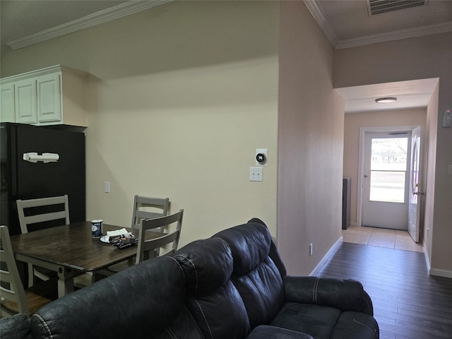 living area featuring visible vents, crown molding, light wood-style flooring, and baseboards