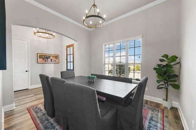 dining space featuring a chandelier, crown molding, baseboards, and wood finished floors