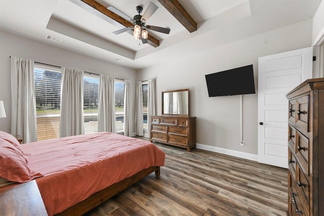 bedroom featuring wood finished floors, visible vents, baseboards, a tray ceiling, and beamed ceiling