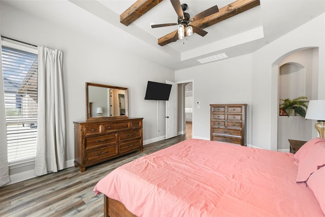 bedroom with baseboards, visible vents, a raised ceiling, and wood finished floors