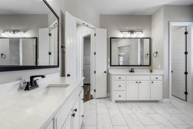 full bath with marble finish floor, walk in shower, two vanities, and a sink