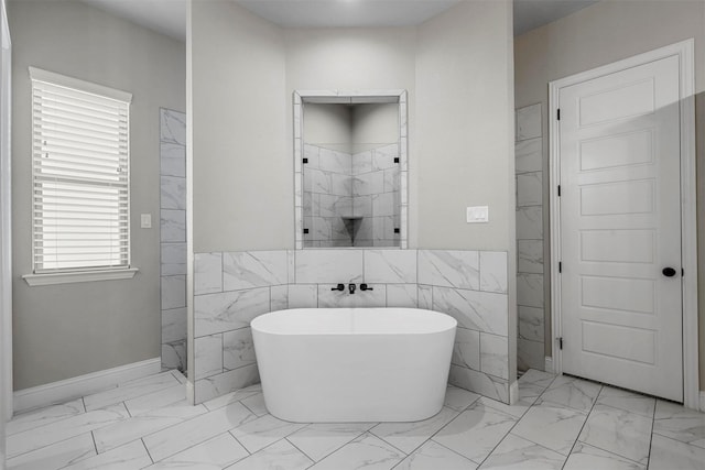 bathroom with marble finish floor, tile walls, a freestanding bath, and tiled shower