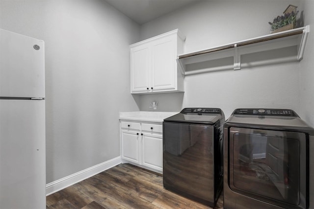 laundry area with dark wood-type flooring, washing machine and dryer, cabinet space, and baseboards