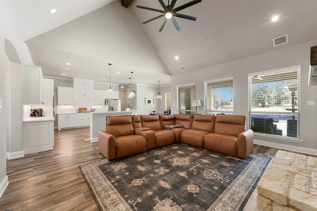 living area with visible vents, ceiling fan, wood finished floors, high vaulted ceiling, and beamed ceiling