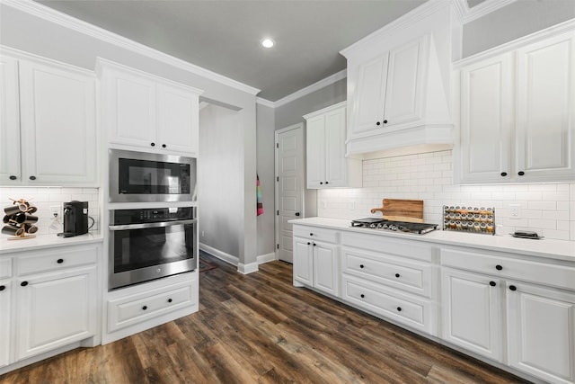 kitchen with crown molding, stainless steel appliances, light countertops, white cabinetry, and premium range hood