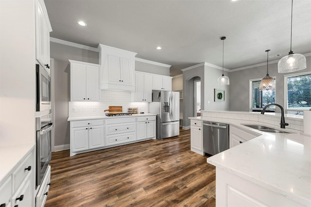 kitchen with dark wood-style flooring, backsplash, appliances with stainless steel finishes, white cabinets, and a sink