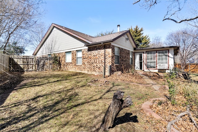 exterior space with a yard, brick siding, and fence