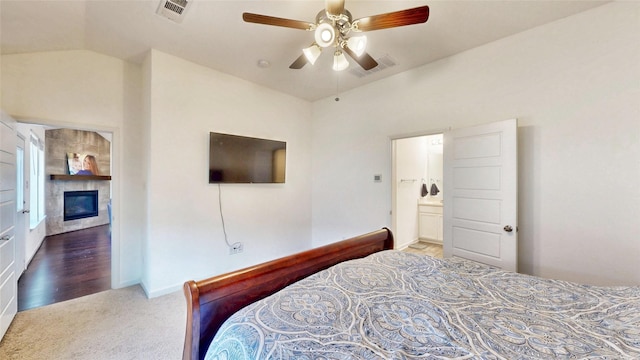 carpeted bedroom with a ceiling fan, lofted ceiling, visible vents, and a fireplace