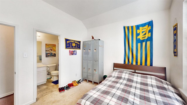 bedroom featuring ensuite bathroom, vaulted ceiling, and light colored carpet