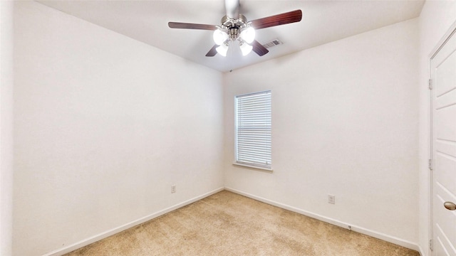 spare room featuring light carpet, a ceiling fan, visible vents, and baseboards