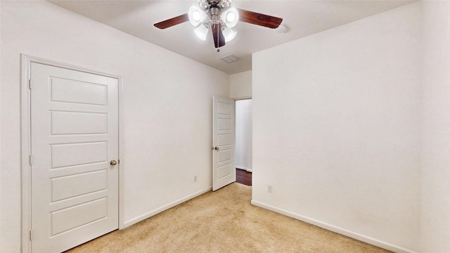 unfurnished bedroom featuring light carpet, a ceiling fan, visible vents, and baseboards