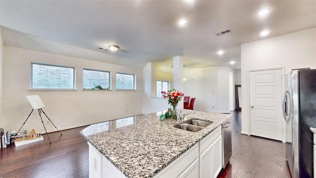 kitchen featuring a center island with sink, light stone countertops, stainless steel appliances, white cabinetry, and a sink