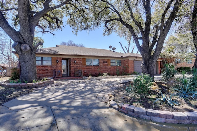 ranch-style house featuring a garage, concrete driveway, and brick siding