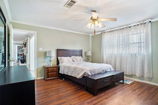 bedroom with ornamental molding, wood finished floors, visible vents, and baseboards