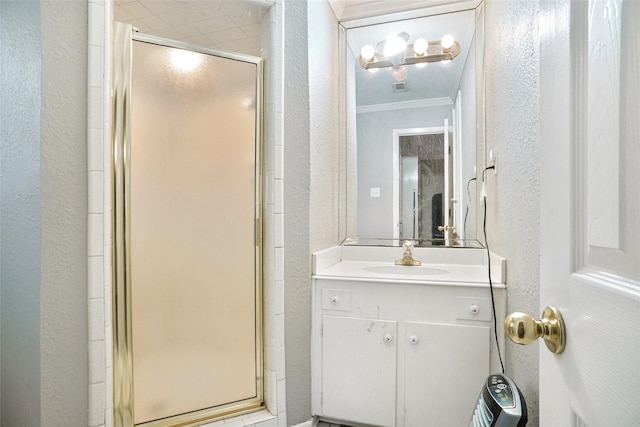 full bath with a textured wall, vanity, visible vents, ornamental molding, and a stall shower