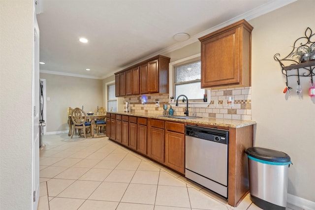 kitchen featuring light stone counters, a sink, stainless steel dishwasher, brown cabinets, and tasteful backsplash