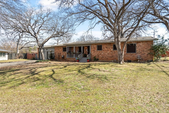 ranch-style home featuring brick siding, covered porch, an attached garage, a front yard, and fence