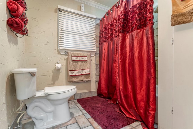 bathroom featuring toilet, ornamental molding, and a textured wall