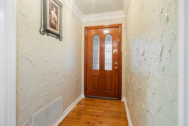 doorway to outside with baseboards, visible vents, a textured wall, ornamental molding, and wood finished floors