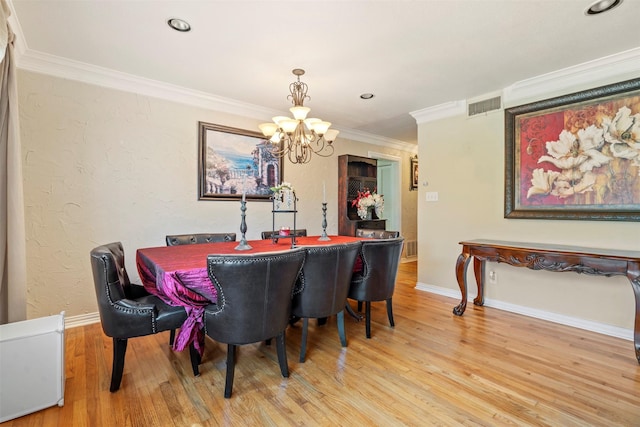 dining room with light wood finished floors, baseboards, visible vents, ornamental molding, and a chandelier