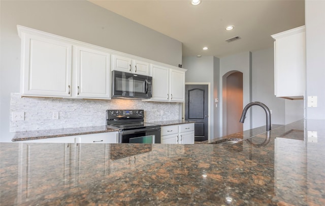 kitchen with dark stone counters, white cabinets, visible vents, and black appliances