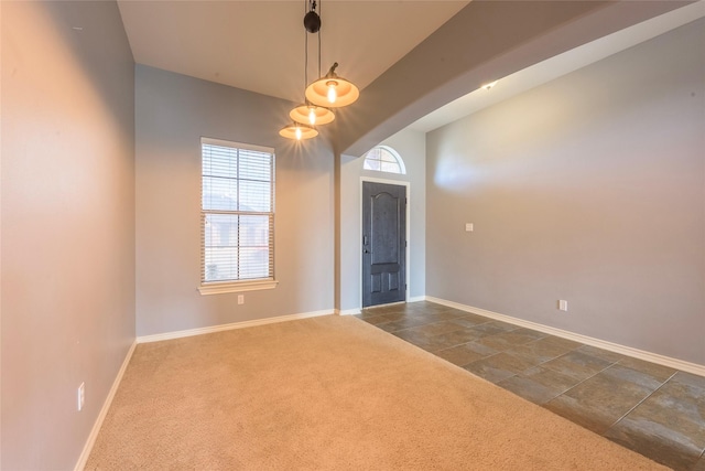 foyer entrance with baseboards, dark carpet, and arched walkways