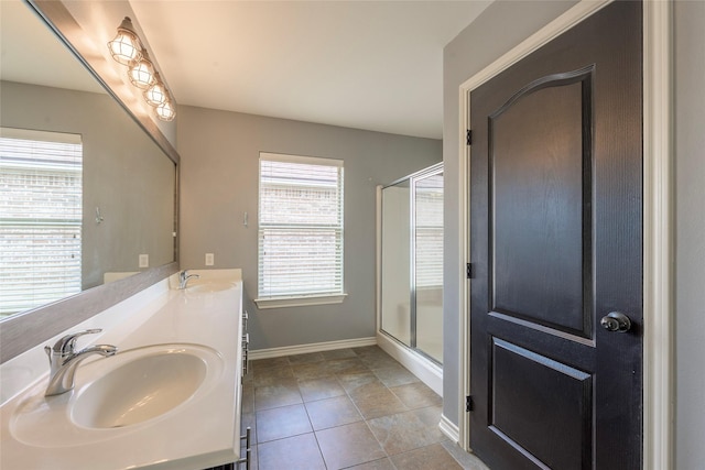 full bath featuring double vanity, a stall shower, tile patterned flooring, and a sink