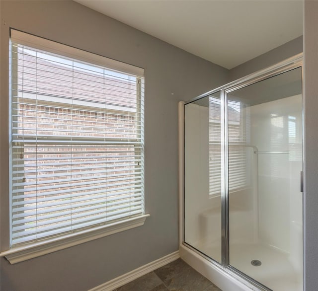 bathroom with a stall shower, tile patterned flooring, and baseboards