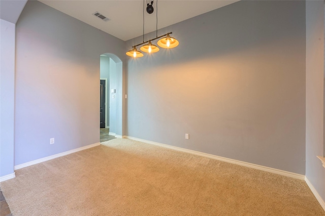 carpeted empty room featuring arched walkways, visible vents, and baseboards