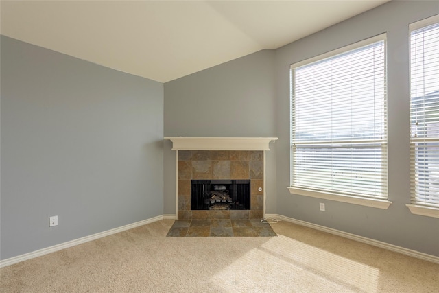 unfurnished living room with carpet floors, lofted ceiling, a fireplace, and baseboards